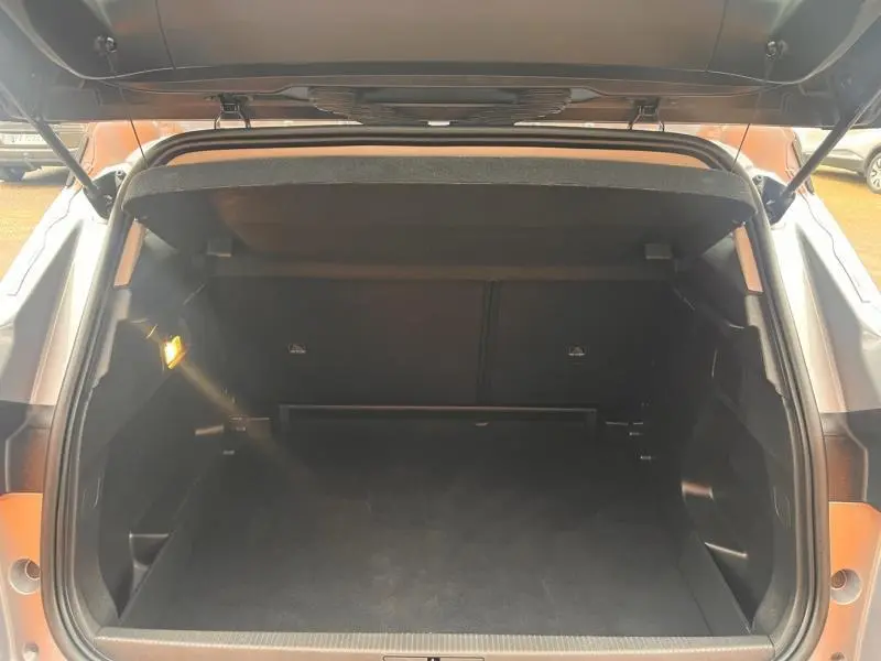 Coffre ouvert vu de l'arrière de l'Opel Grandland gris Kontrast Métallisé, espace de chargement vide et éclairage intérieur allumé.