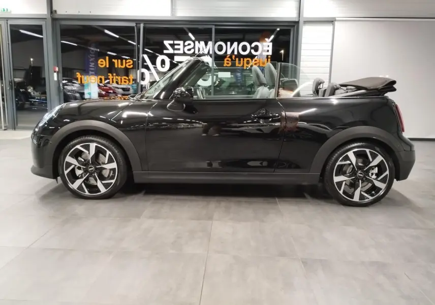 Vue de profil côté gauche d'un cabriolet MINI Cooper C Classic noir avec capote ouverte et jantes 16 pouces design 4-Square Spoke.