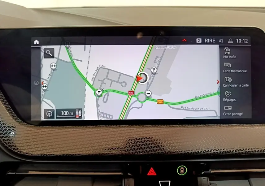 Écran tactile central de navigation 3D affichant une carte routière dans une BMW Série 1 bleue, vue intérieure.