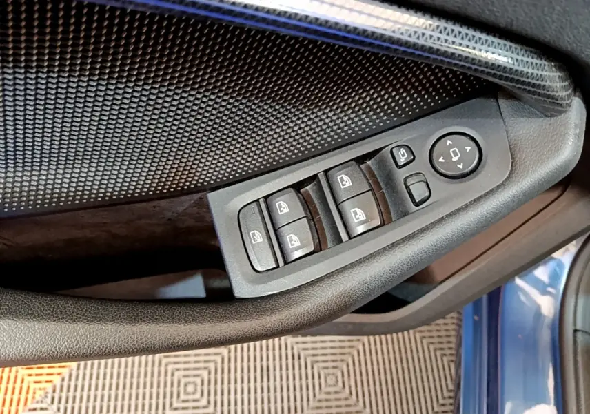 Détail des commandes des vitres et rétroviseurs sur la porte côté gauche d’une BMW Série 1 bleu 2023.