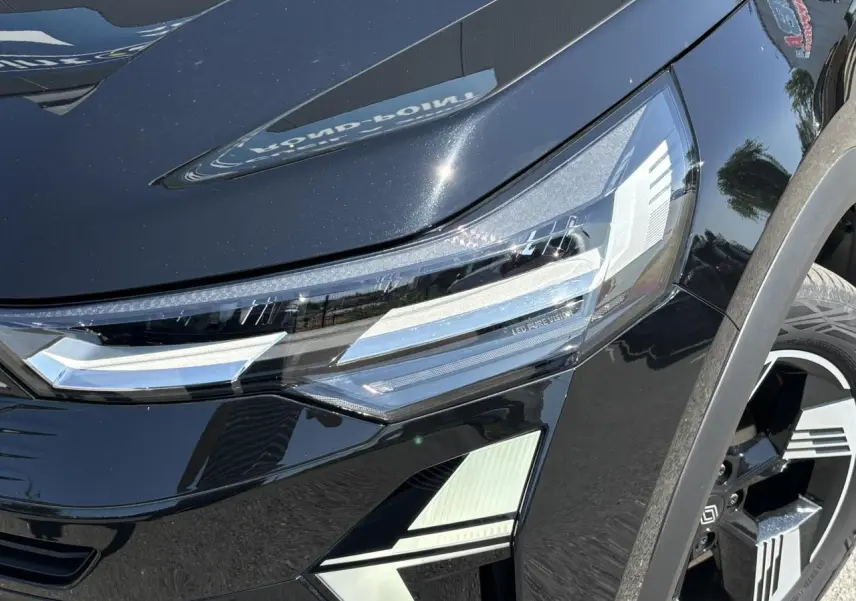 Gros plan sur le phare avant droit et la roue d’une Renault SYMBIOZ noire étoile avec détails LED Pure Vision.