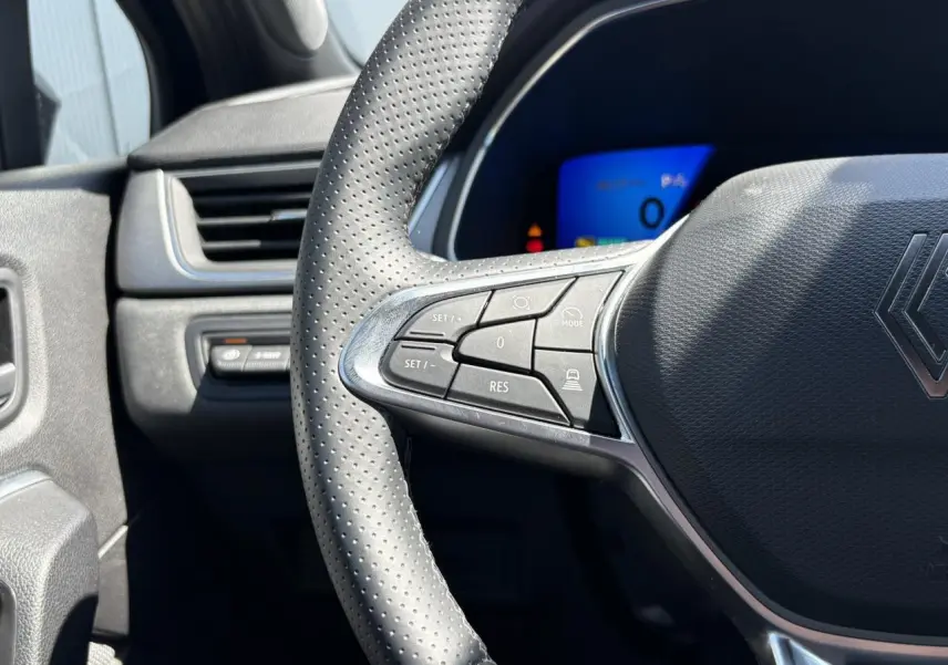 Gros plan sur le volant perforé côté gauche du Renault SYMBIOZ 2025 avec commandes intégrées et tableau de bord numérique.