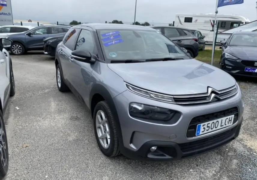 Citroën C4 Cactus gris clair vue 3/4 avant droit sur parking avec phares et calandre caractéristiques.