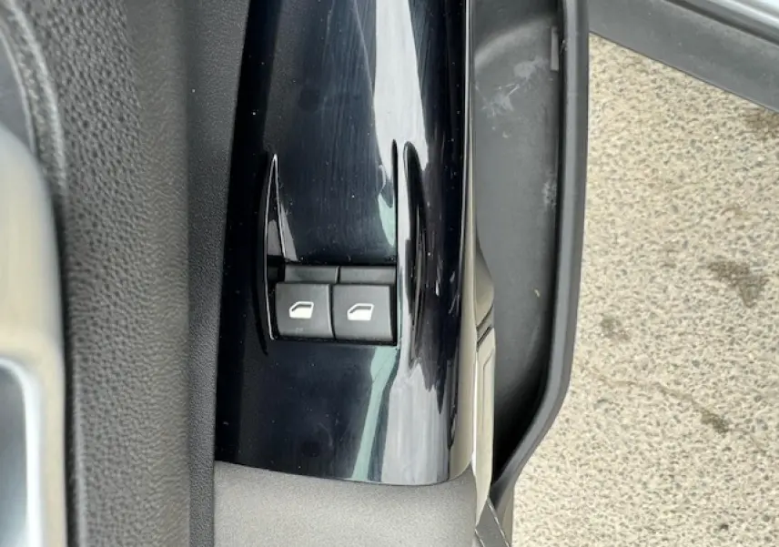 Gros plan sur les commandes de lève-vitres côté conducteur d'une Citroën C4 Cactus gris clair, portière ouverte.