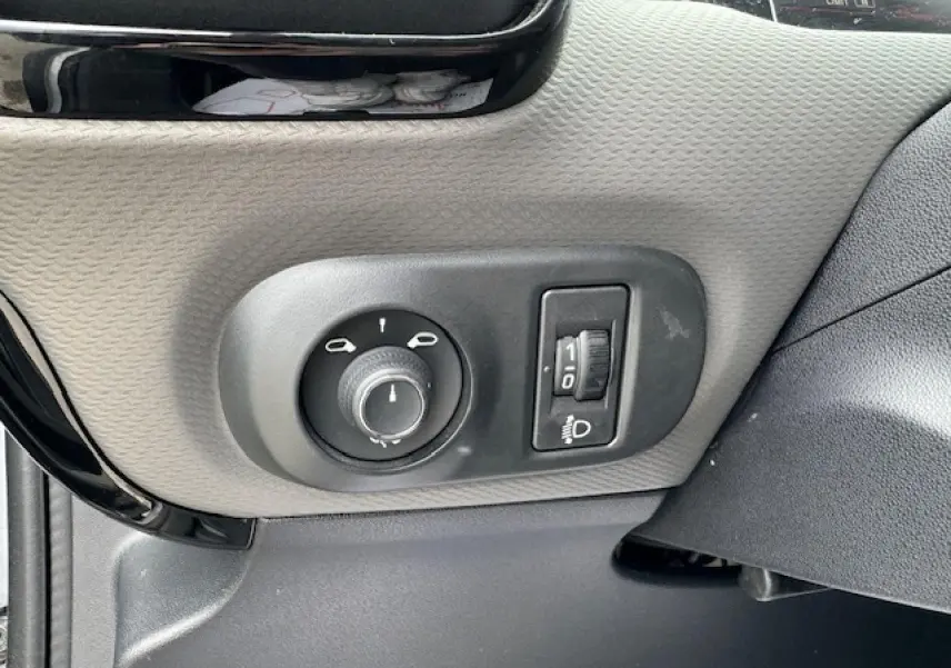 Gros plan sur les commandes d’éclairage et réglage des phares à gauche du tableau de bord d’une Citroën C4 Cactus gris clair 2020.