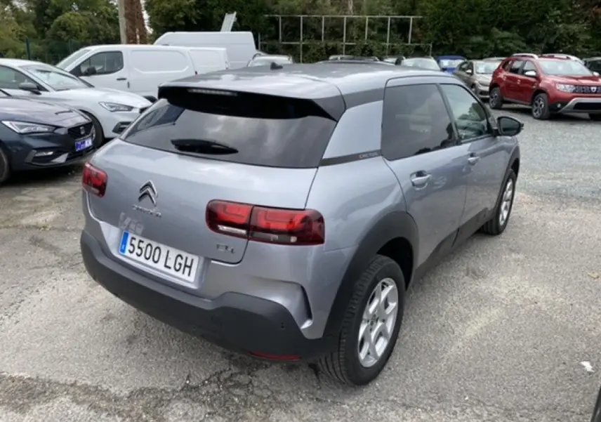 Vue 3/4 arrière droite d'une Citroën C4 Cactus gris clair avec vitres teintées et jantes acier 15 pouces.