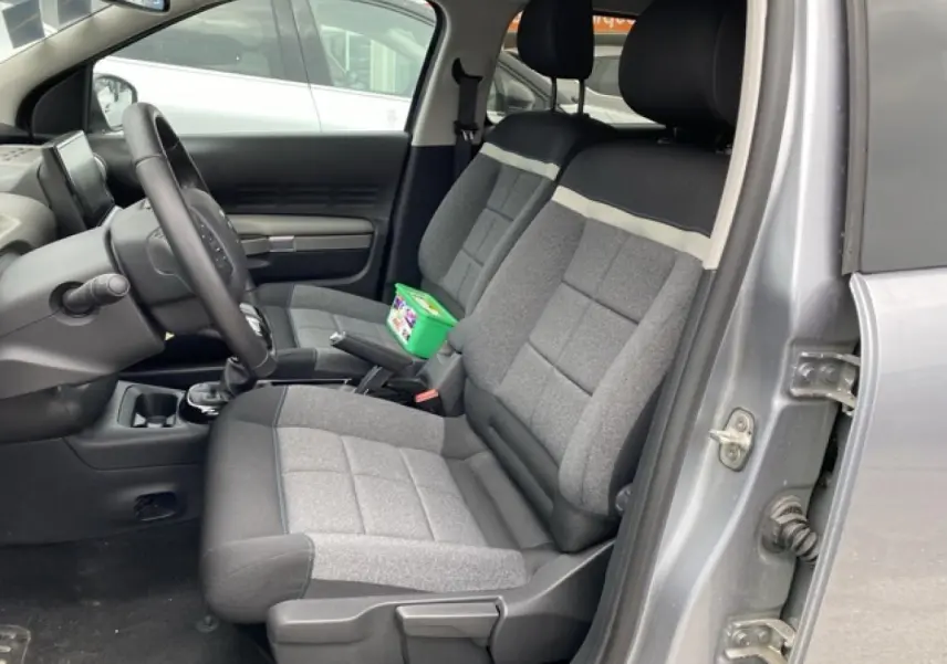 Vue intérieure côté conducteur de la Citroën C4 Cactus 2020 gris clair avec sièges tissu bicolores et volant réglable.