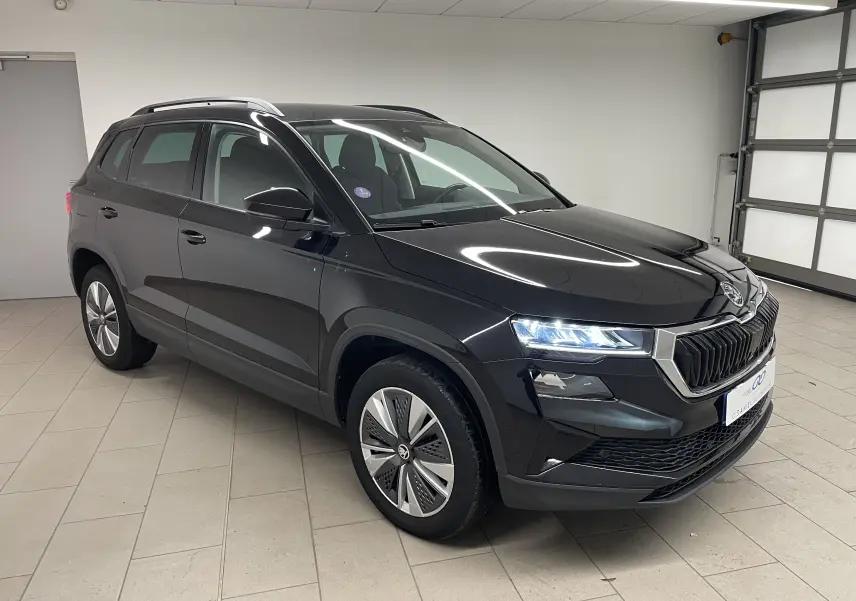 SUV Skoda Karoq noir Magic nacré vu en 3/4 avant droit avec phares LED allumés dans un garage.