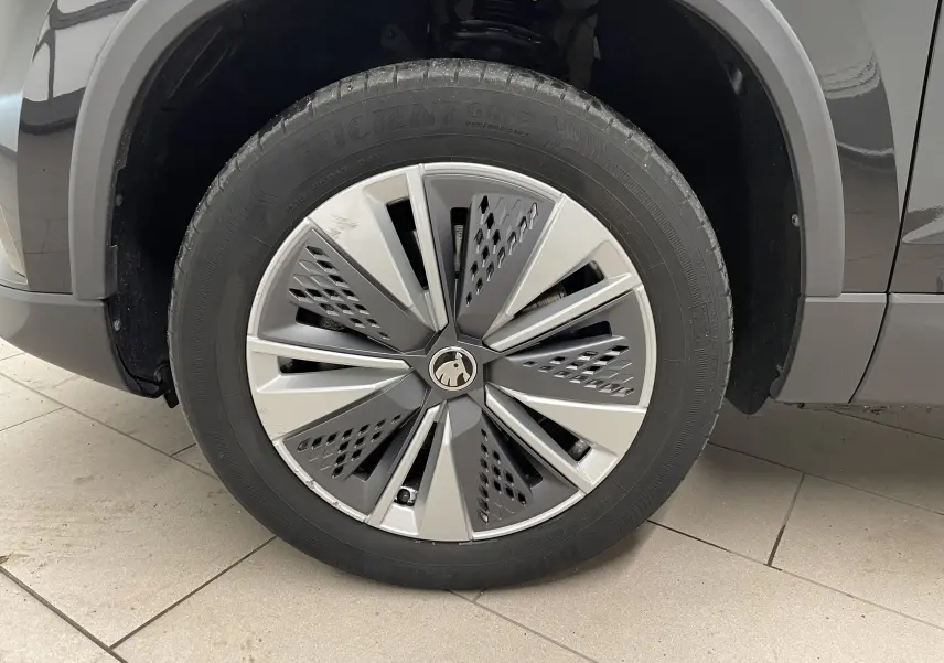 Gros plan sur la roue avant gauche d'un Skoda Karoq noir Magic nacré avec jante alliage au design moderne.