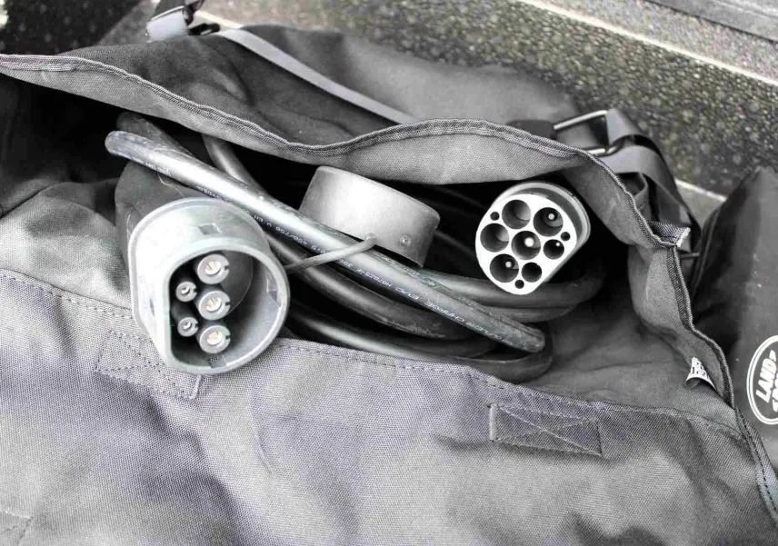 Câble de recharge hybride dans un sac gris avec logo Land Rover, accessoire du Range Rover Evoque gris métal 2023.