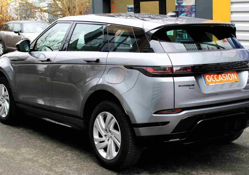 Vue intérieure côté gauche des sièges arrière bicolores noirs et gris du Range Rover Evoque 2023 gris métal avec accoudoir central rabattable.
