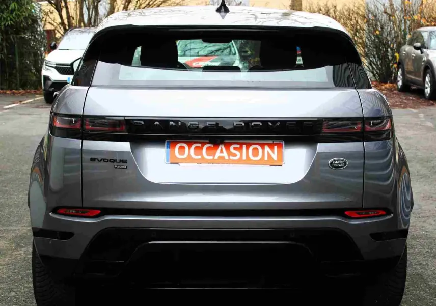 Vue intérieure côté gauche des sièges arrière bicolores noir et blanc du Range Rover Evoque gris métal 2023 hybride rechargeable.