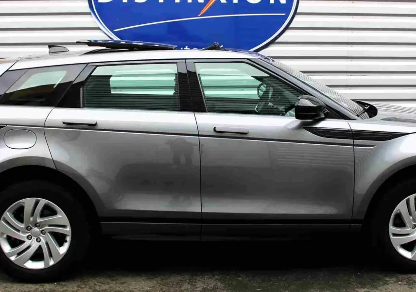 Vue intérieure côté gauche du Range Rover Evoque gris métal 2023, mettant en valeur les sièges bicolores et la console centrale moderne.