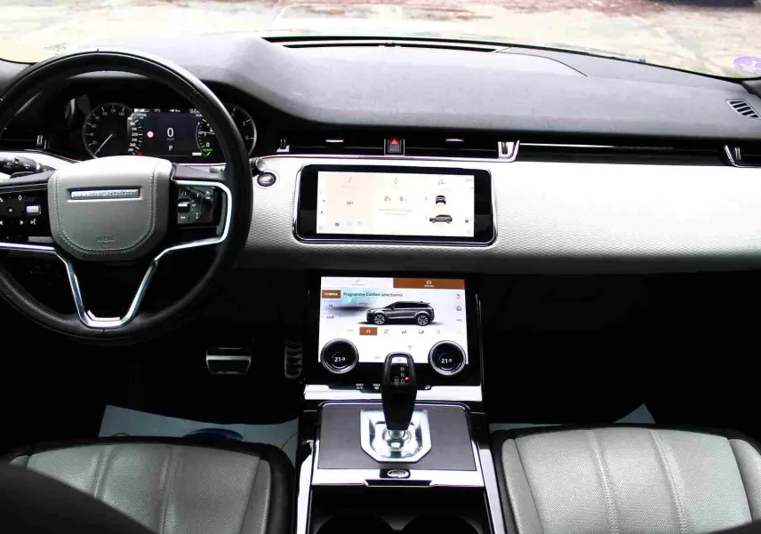 Range Rover Evoque gris métal 2023 en 3/4 avant droit, hybride rechargeable, devant un bâtiment commercial.