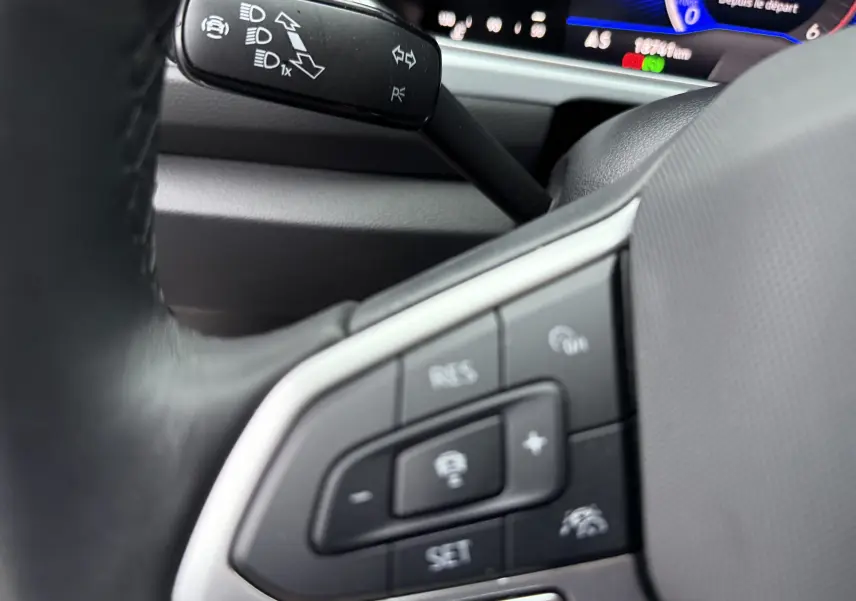 Gros plan sur la commande au volant du Volkswagen T-Roc 2.0 TDI 150ch Life Plus 2025, intérieur noir avec affichage digital.