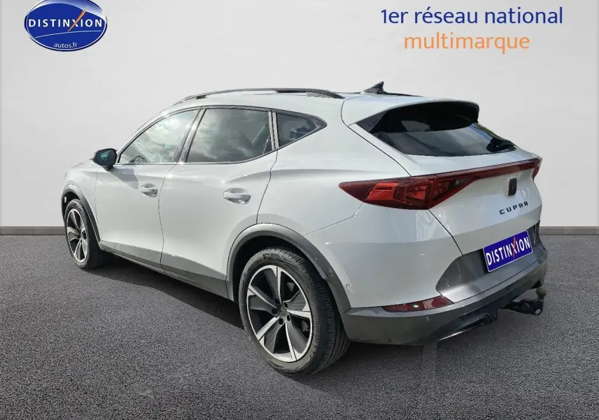 Vue 3/4 arrière droite d'un CUPRA Formentor blanc avec jantes alu et attelage visible sur fond neutre.