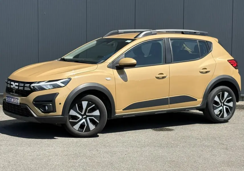 Vue latérale droite d'une Dacia Sandero Stepway beige Safari avec barres de toit et jantes distinctives.