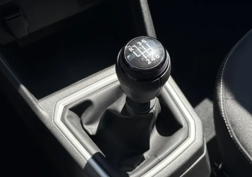 Gros plan sur le levier de vitesses manuel noir de la Dacia Sandero Stepway 2025, intérieur gris et siège tissu visible.