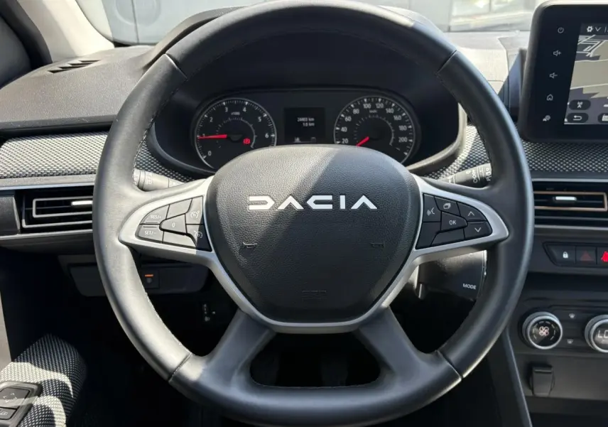 Vue rapprochée du volant noir de la Dacia Sandero Stepway 2025 avec commandes intégrées et tableau de bord numérique.