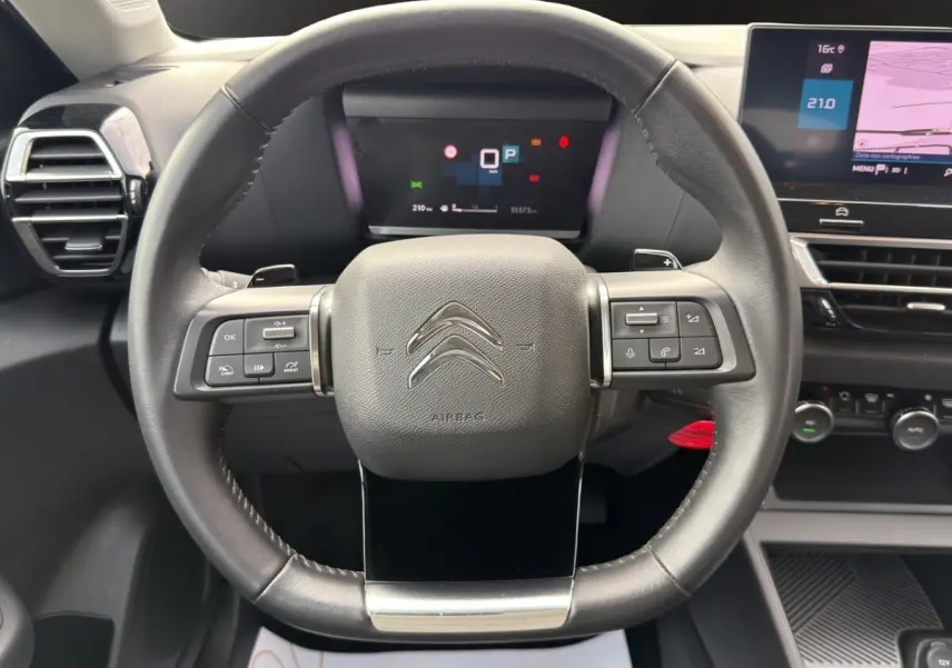 Vue frontale du volant cuir noir de la Citroën C4 2023 avec commandes multifonctions et tableau de bord digital.
