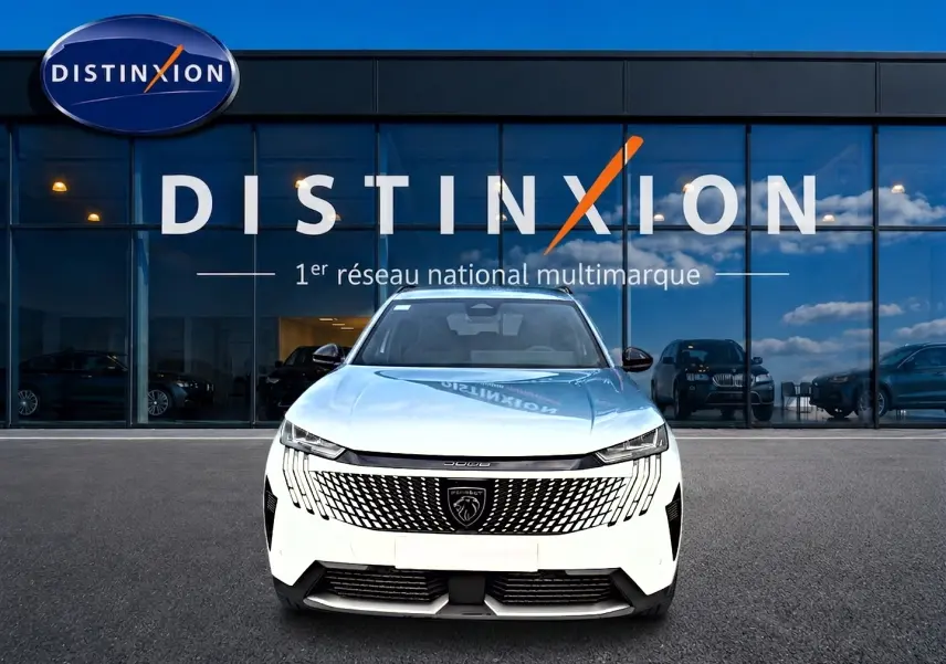 Vue avant centrée d’un Peugeot 5008 Hybrid 145 allure blanc devant une vitrine avec logo Distinxion.