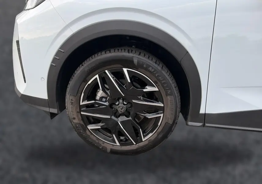 Gros plan sur la roue avant droite noire et argentée du Peugeot 5008 blanc, soulignant le design des jantes alu.