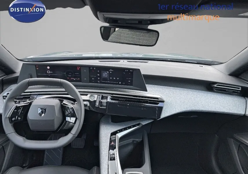 Vue intérieure avant du Peugeot 3008 Hybrid 2025 avec tableau de bord moderne et volant compact gris foncé.