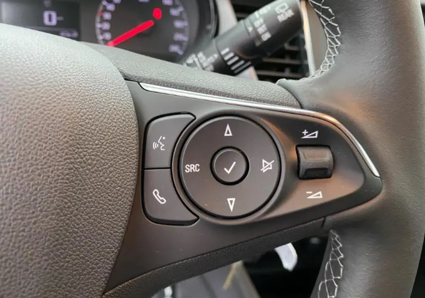 Gros plan sur les commandes du volant en cuir noir de l’Opel Crossland gris métallisé, avec boutons multifonctions visibles.