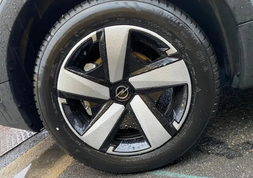 Gros plan sur la roue avant droite d'un Opel Crossland gris métallisé 2022 avec jante bicolore au design moderne.