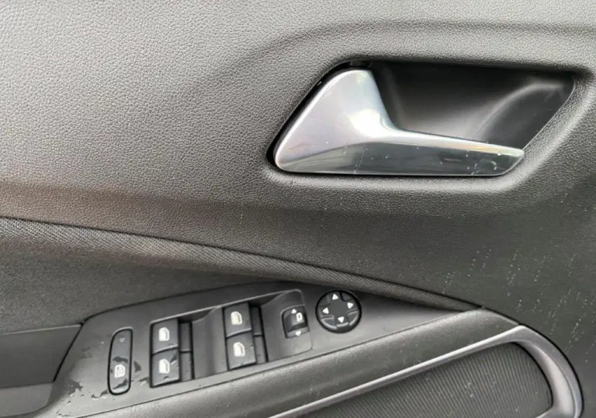 Poignée intérieure et commandes des vitres côté gauche d'un Opel Crossland gris métallisé 2022 en gros plan.