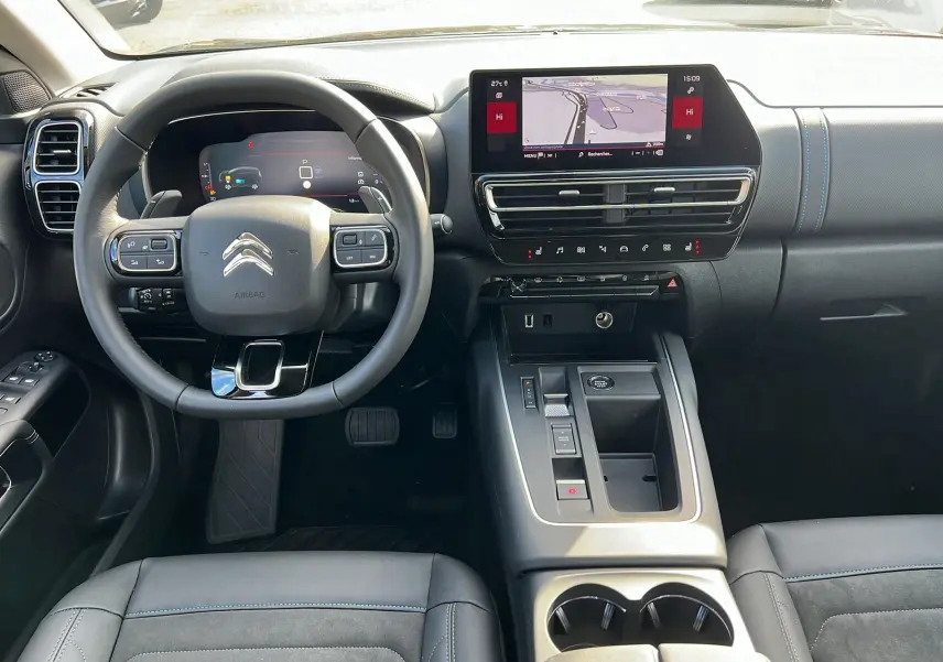 Intérieur du Citroën C5 Aircross Hybrid 2025, vue du poste de conduite avec volant multifonction et écran tactile central.
