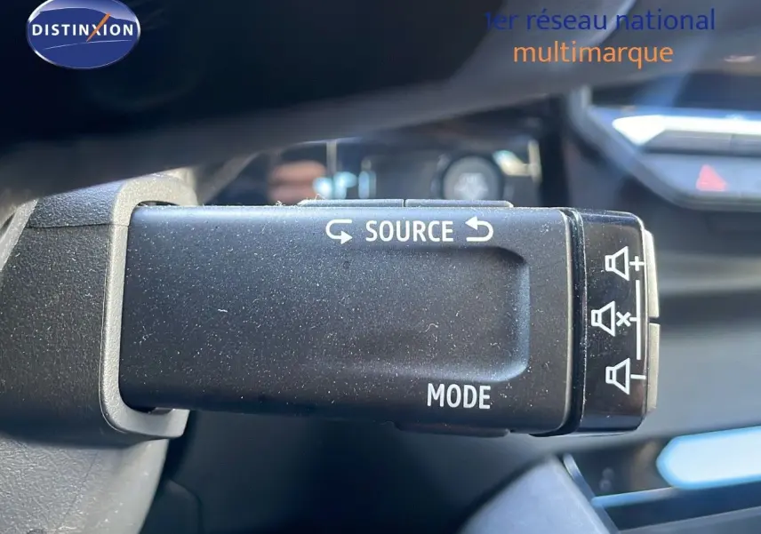 Gros plan sur la commande au volant du Renault Austral blanc glacier, montrant les boutons source et mode.