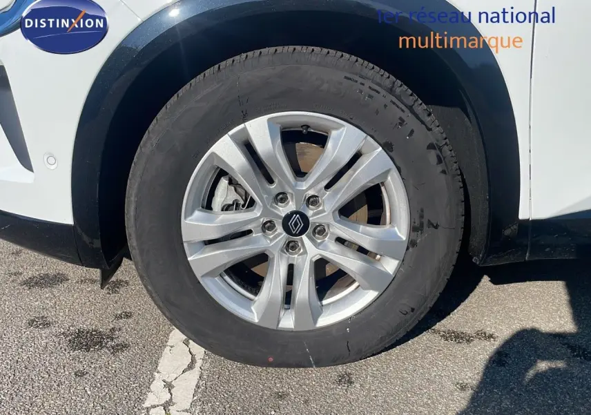 Gros plan sur la roue avant droite du Renault Austral blanc glacier, avec jante argentée et logo Renault central.