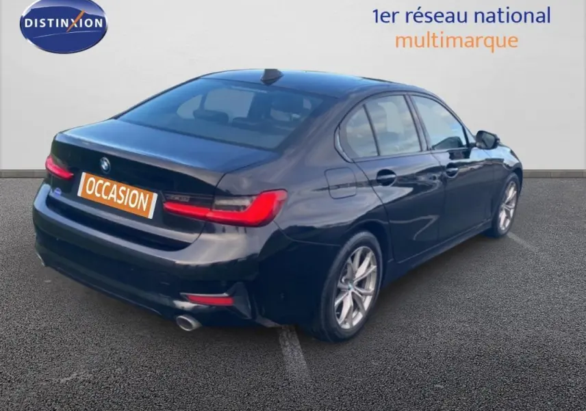 BMW Série 3 G20 noire vue 3/4 arrière droit, avec jantes alliage 17 pouces et feux arrière allumés.