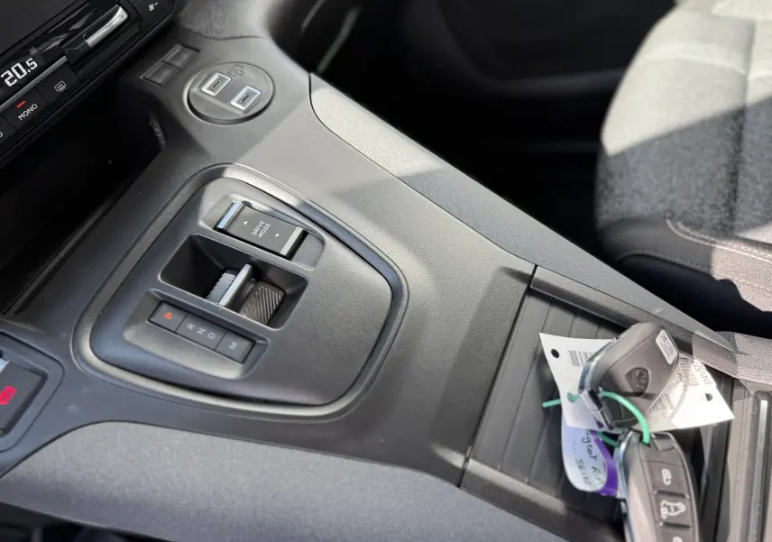 Gros plan sur la console centrale noire du Peugeot Rifter Allure 2026, avec levier de boîte auto et clés posées.
