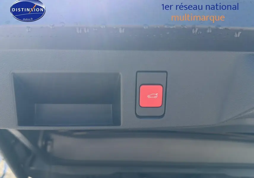 Gros plan sur le bouton rouge d'ouverture du hayon du Citroën C5 Aircross blanc et noir, vue intérieure arrière du coffre.