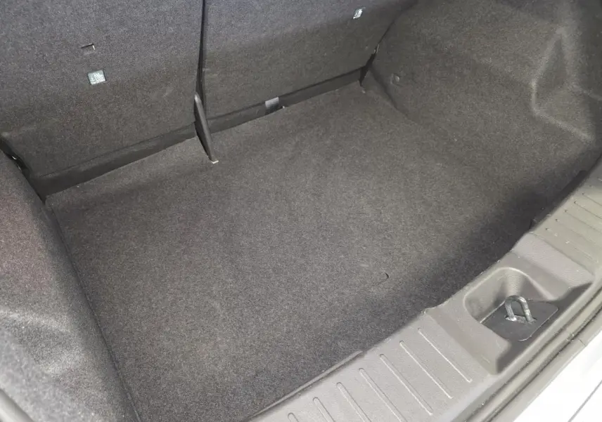 Coffre vide vu de dessus du Nissan Juke 2025 gris, avec tapis de sol et ancrage visible.