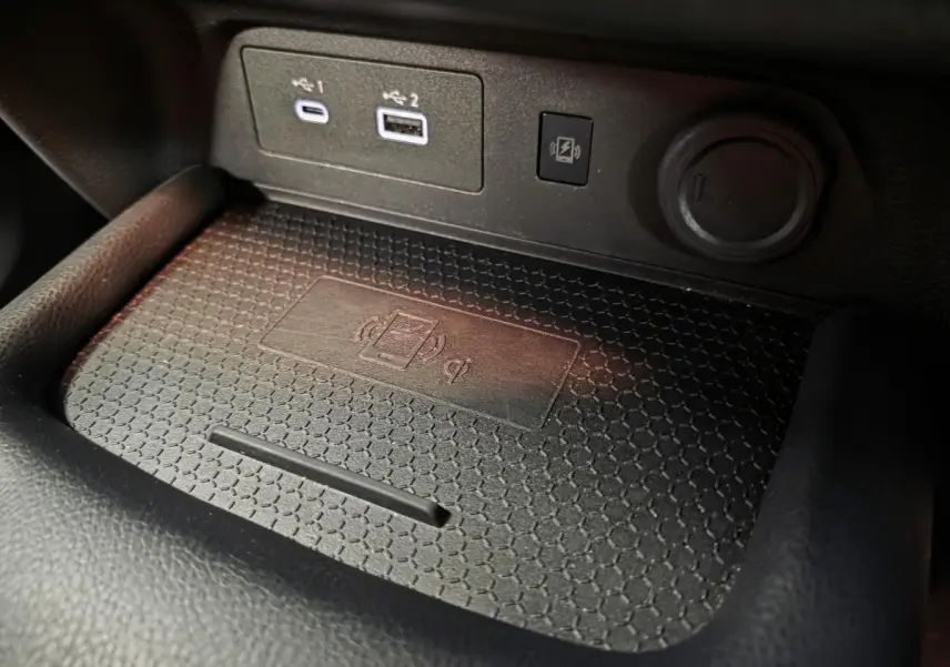 Gros plan sur la zone de recharge sans fil et ports USB du Nissan Juke gris, intérieur noir texturé.