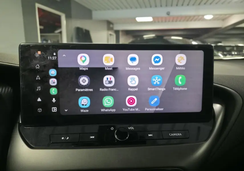 Écran tactile central du Nissan Juke 2025 affichant des applications de navigation et communication, intérieur noir.