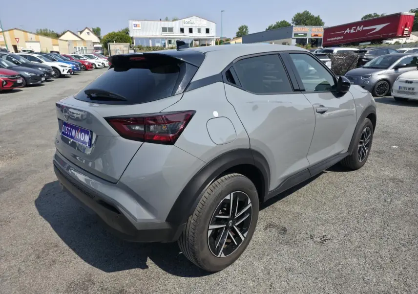 Nissan Juke gris métallisé vue 3/4 arrière droit avec jantes alliage et vitres teintées sur parking.