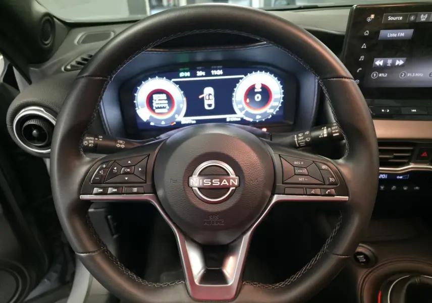 Vue rapprochée du volant en cuir noir du Nissan Juke 2025 avec tableau de bord digital et commandes intégrées.