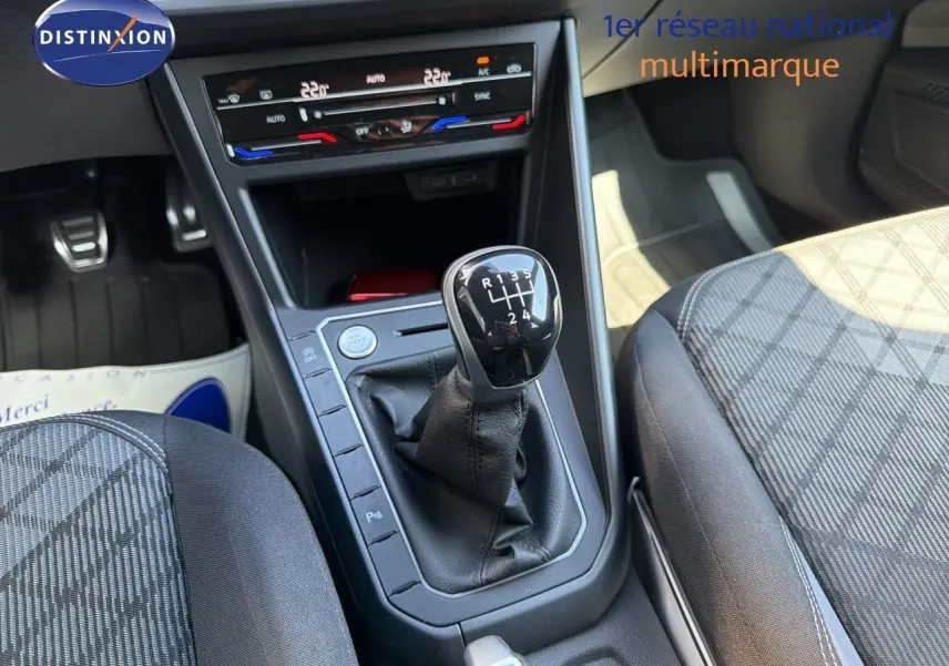 Gros plan sur la console centrale d'une Volkswagen Polo rouge Roi 2023, mettant en valeur le levier de vitesses manuel.