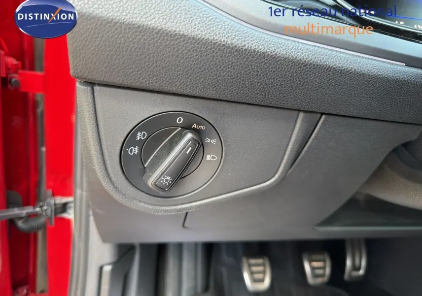 Gros plan sur le bouton de commande des phares dans l’habitacle d’une Volkswagen Polo rouge roi, côté conducteur.