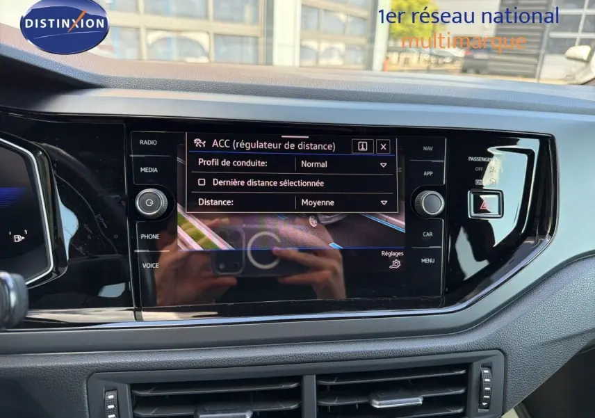 Vue rapprochée de l’écran tactile central de la Volkswagen Polo rouge Roi 2023, affichant le régulateur de distance ACC.