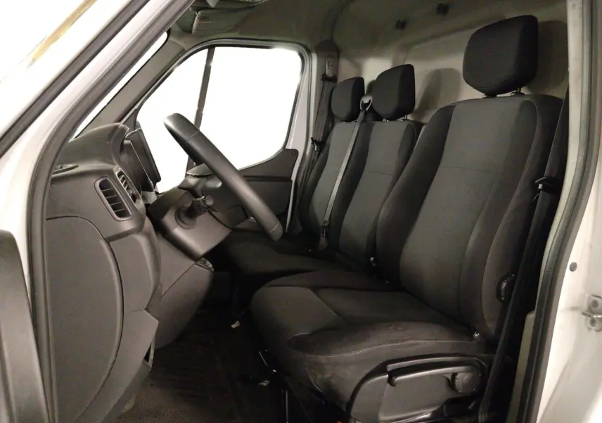 Vue intérieure côté conducteur du Renault Master blanc 2023, montrant les trois sièges noirs et le tableau de bord.