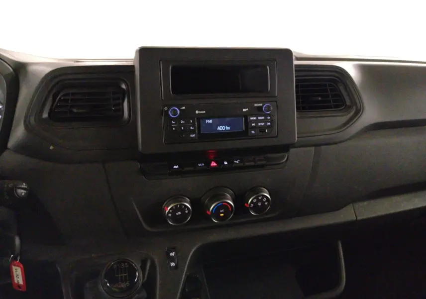 Vue intérieure du tableau de bord du Renault Master 2023, avec console centrale noire et commandes de climatisation visibles.