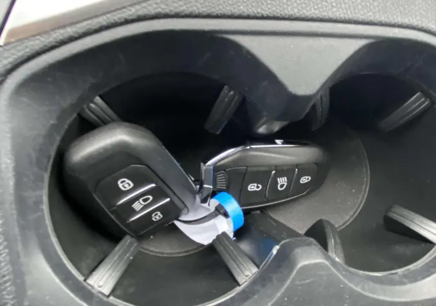 Gros plan sur deux clés de contact Peugeot 3008 posées dans les porte-gobelets noirs du véhicule.