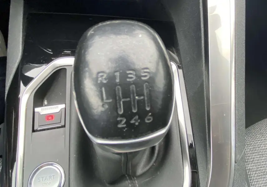 Le levier de vitesse manuel noir de la Peugeot 3008 blanc nacré, vu en gros plan depuis l'intérieur.