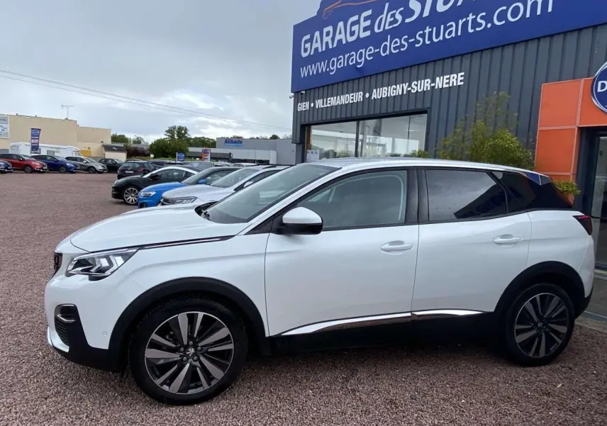 Profil droit du Peugeot 3008 blanc nacré 2017 avec jantes alliage 19 pouces et vitres surteintées, stationné devant un garage.