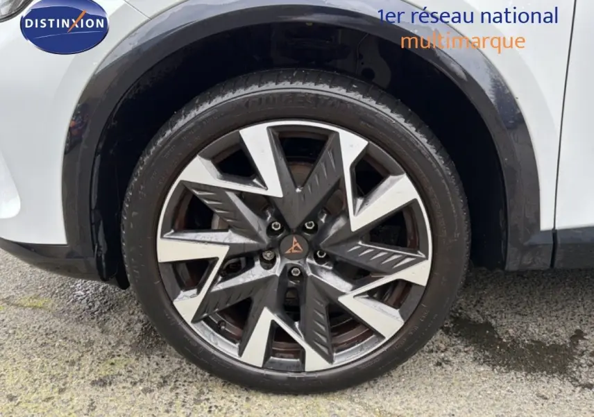 Gros plan sur la roue avant droite d’une CUPRA Formentor blanc neige métal avec jante bi-ton au design anguleux.